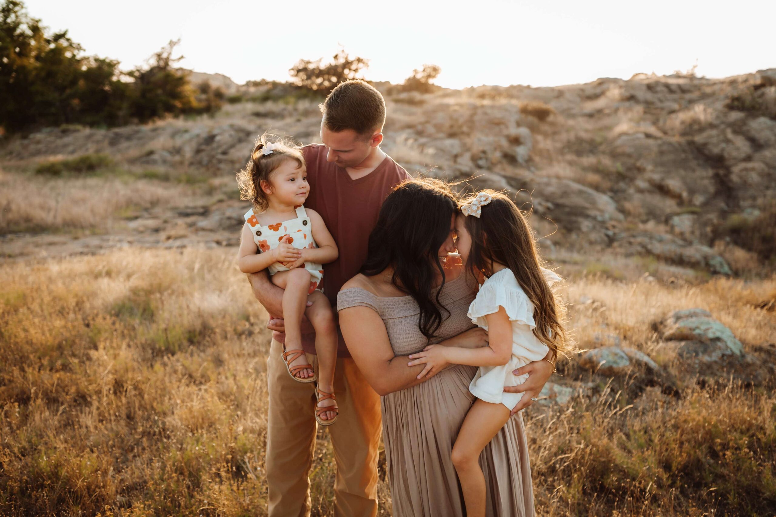 beautiful family photo of four family members in a field and mountains.