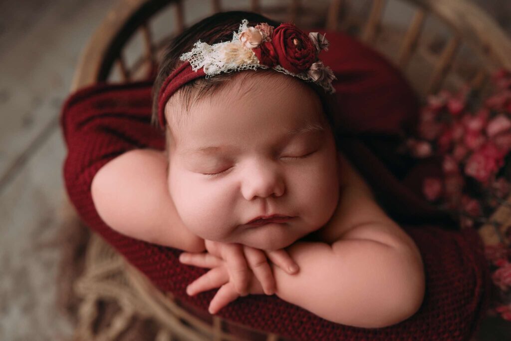 Beautiful newborn photo of a baby swaddled in a red wrap.