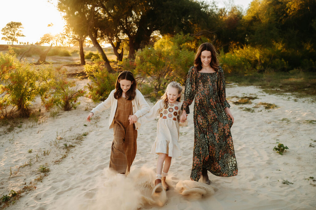 Golden hour photo of three sisters holding hands in Fort Worth, Texas